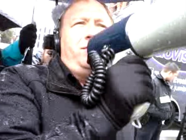 Alex Jones bullhorns the police at the barricades to Dealey Plaza while broadcasting live on his syndicated radio talk show.